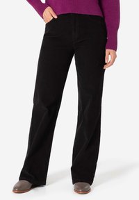 Black corduroy pants with a straight-leg cut and subtle texture, featuring side pockets and a high waist. Worn with a purple sweater.