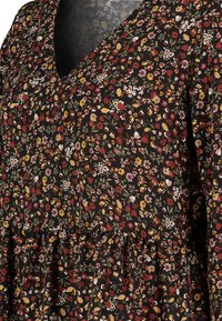 Zwart bloemenjurk met een V-hals, versierd met diverse kleine bloemen in rood, geel en wit op textuurachtig zwart stof, met een gelaagde onderkant.