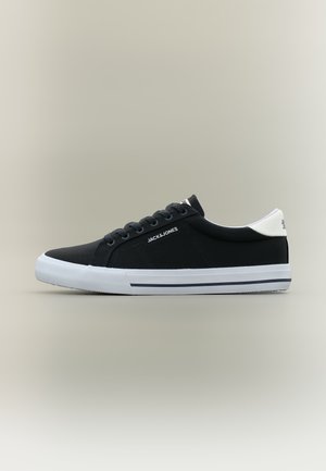 Fekete alacsony szárú sportcipő fehér talppal, fehér sarokfüllel, a "JACK & JONES" logóval az oldalon és fekete fűzőkkel, semleges háttér előtt.