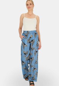 Niebieskie palazzo z wzorem w liście, o luźnym kroju, z czarnym wzorem liści, elastycznym pasem i bocznymi kieszeniami. Noszone z białą bluzką.
