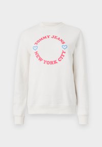 Hvit hettegenser med en rund grafikk som har "TOMMY JEANS" i rosa og "NEW YORK CITY" under, akkompagnert av blå hjerter. Myk bomullsdel.