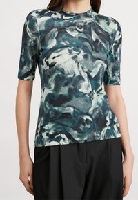 Kortärmad topp i blandad tygkvalitet med ett abstrakt mönster i blått, grönt och vitt; rund halsringning, figurnära passform.