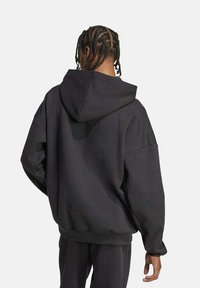 Sudadera negra de gran tamaño con capucha con cordón, ajuste holgado, ribete acanalado en el dobladillo y los puños, confeccionada en una suave tela texturizada.