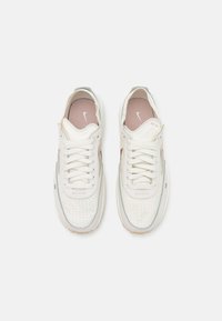 Par de zapatillas Nike blancas perforadas con plantillas rosas, detalles en verde claro y cordones blancos, vistas desde arriba sobre un fondo blanco.