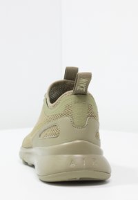 Olivově zelené tenisky Nike s vrchní částí z prodyšné síťoviny, texturovanými doplňky a polstrovaným podpatkem. Obsahují poutko a na podrážce je embosovaný nápis "AIR".