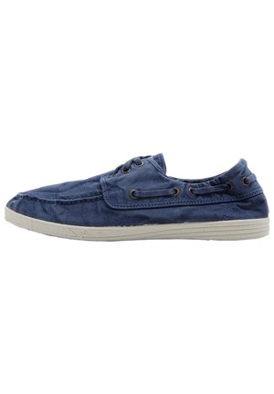Blauwe canvas instapper met ronde neus, zachte stoffen textuur en beige rubberen zool. Voorzien van metalen oogjes voor de veters en stiksels als accent.