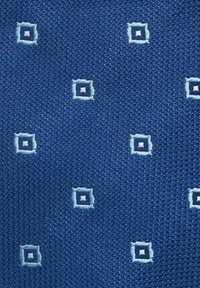 Blått tyg med en texturerad väv, prytt med ett mönster av små broderade rutor i ljusblått och vitt, jämnt fördelade över hela ytan.