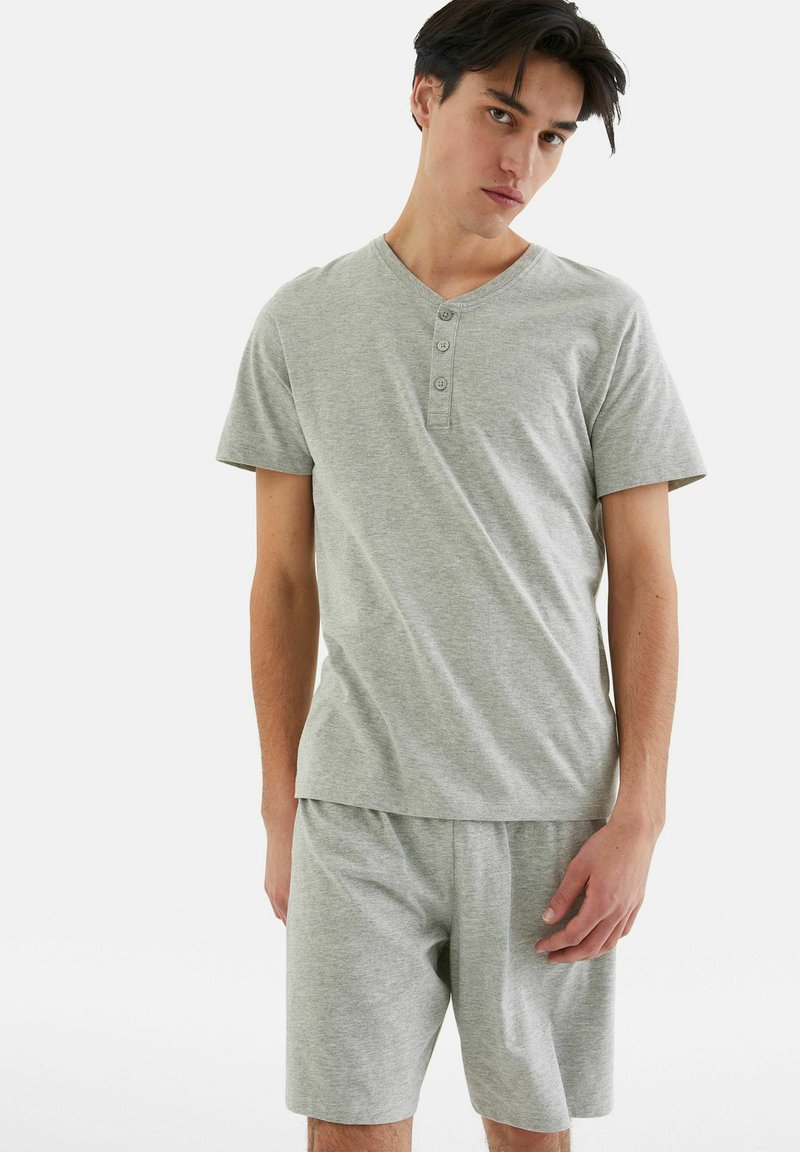 Hellgraues Baumwoll-Loungewear-Set mit einem kurzärmeligen Henley-Shirt mit Knöpfen und passenden Shorts, beide in lockerer Passform.