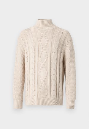 Pull en torsades de couleur crème avec col roulé, orné de motifs en losange et de nœuds, avec des poignets et un ourlet côtelés, présenté sur un fond uni.