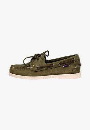 Green suede boat shoe with lace-up design, contrasting white rubber sole, and metal eyelets. Features logo tag on the side.
