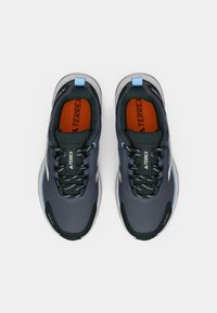 Γκρι αθλητικά παπούτσια με υφή στην επιφάνεια, μαύρα κορδόνια και μπλε λεπτομέρειες. Διαθέτουν μαλακή σόλα και έντονη πορτοκαλί εσωτερική σόλα.