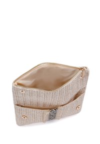 Bolsa de tela trenzada en color beige con cierre de cremallera y un interior liso. Presenta una correa decorativa con un patrón en blanco y negro.
