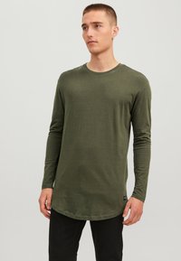 Olijfgroen T-shirt met lange mouwen van zachte katoen, voorzien van een ronde hals en een gebogen zoom, met een zwart label accent aan de zijkant.