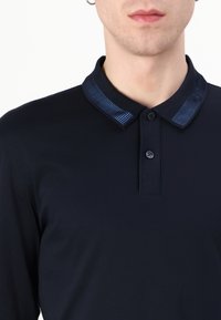 Ναυτικό πόλο μπλούζα μακρύ μανίκι με υφή στη μπλε ρίγα στο γιακά, τετράκουμπη κλείσιμο και λεία υφή.