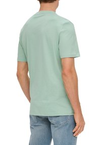 Helles grünes T-Shirt mit kurzen Ärmeln, aus weicher Baumwolle. Klassischer Rundhalsausschnitt, taillierte Form, glatte Textur, ohne sichtbare Muster oder Akzente.