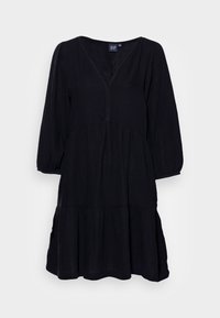 Svart klänning med v-ringning, långa puffärmar och lager på lager nederkant. Tillverkad av lätt tyg med texturerad yta.