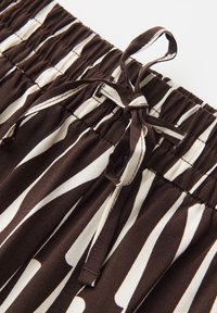 Pantaloni a righe marroni e bianchi con vita elastica e coulisse in tessuto annodata davanti, realizzati in materiale morbido e leggero.