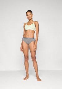 Sostén deportivo verde claro con tirantes ajustables, combinado con bragas de algodón gris con una cinturilla impresa con el logotipo. Diseño simple y sin costuras.