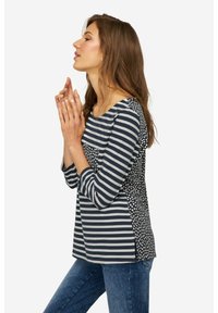 Maglietta a righe navy e crema con maniche a tre quarti, con una sezione posteriore a fantasia. Realizzata in un tessuto morbido e leggero.