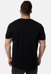 Camiseta negra de manga corta hecha de algodón suave, con un clásico cuello redondo y un corte relajado, con una textura lisa.