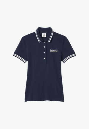 Polo Lacoste azul marino con cuello y mangas a rayas blancas, tapeta de botones y texto "Lacoste Roland Garros Club" en el pecho.