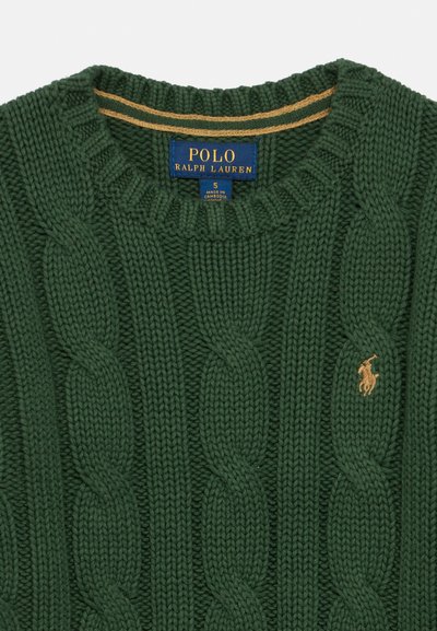 Žalias kabeliu megztas megztinis su apvaliu kaklu, raukšlėtais kraštais ir mažuoju auksiniu logotipu ant krūtinės. Etiketėje parašyta „Polo Ralph Lauren.“
