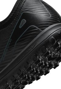 Chaussure de sport noire en matériau texturé, avec des lignes de conception angulaires et une semelle en caoutchouc crantée pour une meilleure traction. Marque "Air Zoom" visible.