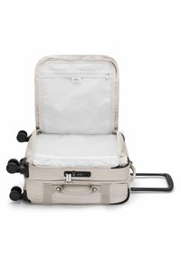 Beige soft-shell suitcase with a zippered compartment, retractable handle, and four wheels. Interior features a mesh pocket and patterned lining.