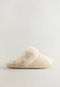 Beige pantofle vyrobené z umělé kožešiny a měkké tkaniny, s kulatým tvarem a polstrovaným vnitřkem pro pohodlí. Plochá gumová podrážka pro trakci.