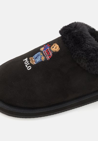 Melnas čības no mīksta zamša, ar pūkainu apkakli, izšūtu lāča dizainu un "POLO" emblēmu sānos.