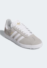 Szare zamszowe sneakersy z białymi akcentami, z trzema białymi paskami, teksturowaną białą podeszwą i złotym logo na języku.