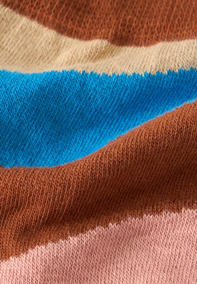 Gros plan sur un tissu tricoté doux avec des rayures horizontales de couleur marron, beige, bleu et rose.