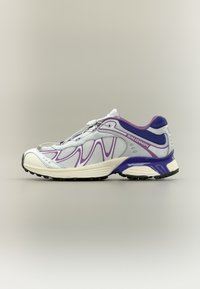 Gray and white athletic shoe with purple accents, mesh upper, cushioned sole, and patterned detailing on the sides and laces.