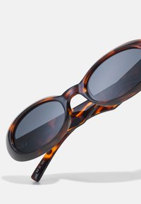 Tortoiseshell sunglasses with oval lenses, dark tinted, and a thick, glossy frame. Includes engraved model numbers on the temple.
