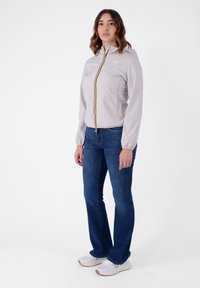 Giacca leggera grigia chiaro con zip e striscia multicolore, abbinata a jeans svasati blu e sneakers bianche. Design semplice e casual.