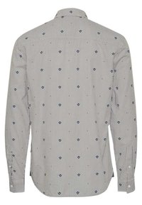 Chemise à manches longues en blanc et marine, ornée de rayures verticales et de petits motifs en forme de feuille. Poignets à bouton et col classique.