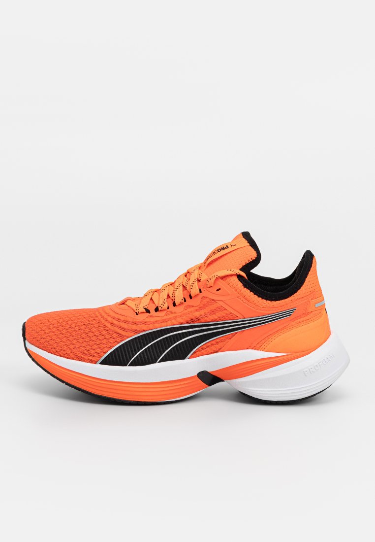 Zapatilla de correr de un brillante color naranja con acentos negros, parte superior texturizada, diseño con cordones, suela blanca acolchada y notable marca PUMA en el costado.