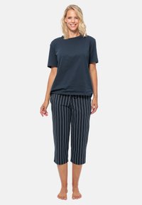 Marineblå bomulls t-shirt med korta ärmar, kombinerad med marinblå och vita randiga capribyxor. Byxorna har ett elastiskt midjeband.