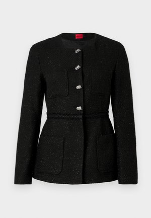 Schwarze Tweedjacke mit rundem Halsausschnitt, langen Ärmeln und silbernen Knopfverschlüssen. Verfügt über zwei Vorderaschen und ein geflochtenes Taillendetail.