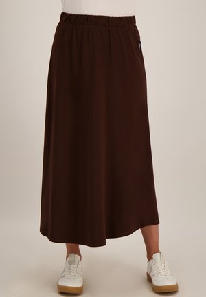 Donkerbruine enkellange rok met elastische tailleband, gedragen met witte sneakers.