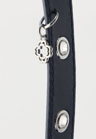 Λουράκι από δέρμα σε ναυτικό μπλε χρώμα με δύο ασημένιες μεταλλικές ροδέλες και ένα ασημένιο κρεμαστό στοιχείο σε σχήμα τετραφυλλιού συνδεδεμένο με μια μικρή αλυσίδα.