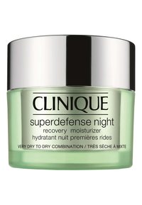 Bocal en verre vert avec un couvercle argenté. L'�étiquette indique "Clinique Superdefense Night Recovery Moisturizer" en noir. La texture semble lisse.