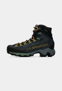 Melnas un zaļas pārgājienu zābaki ar teksturētu virsu, dzeltenām šņorēm, gumijas zoli un zīmolu. Iekļauts Gore-Tex ūdensnecaurlaidīgs materiāls.