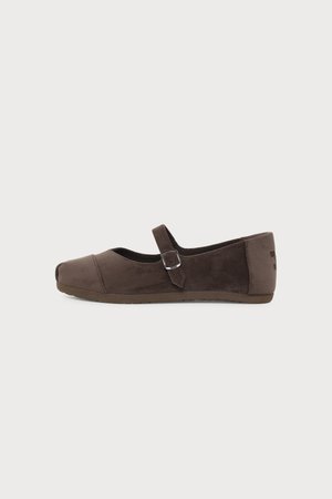 Chaussure plate en daim marron avec un bout arrondi et une bride à boucle ajustable, vue de profil sur fond blanc.