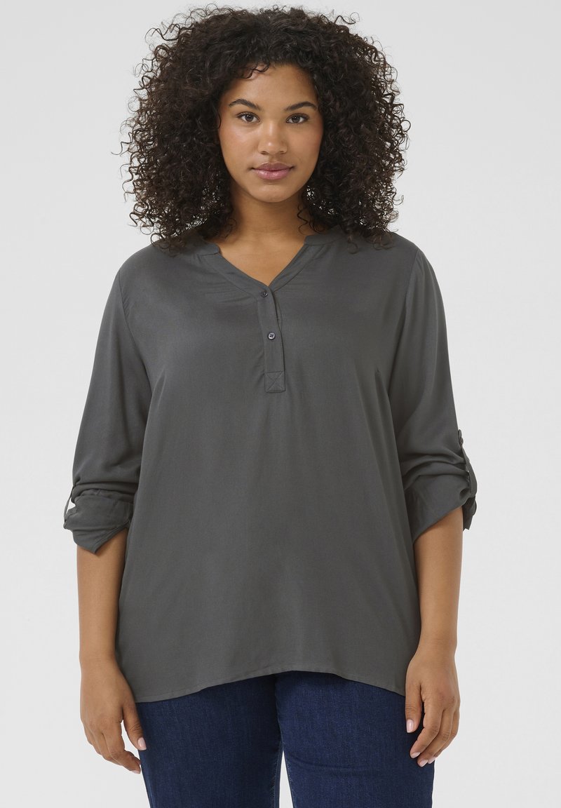 Blouse légère gris foncé avec un décolleté en V, patte de boutonnage et manches roulées, fabriquée dans un tissu lisse. Présente une coupe décontractée.