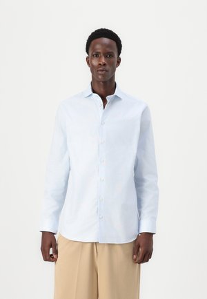 Camisa de manga longa azul-claro feita de algodão, com gola abotoada e placket frontal, apresentando uma bainha reta e mangas com punhos.