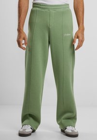 Groene sweatpants van zacht materiaal met een relaxte pasvorm. Voorzien van voornaden en een geborduurd "Prohibited"-logo in het wit.