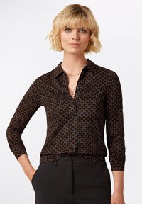 Camicia nera con bottoni, dotata di un motivo geometrico arancione e blu, con colletto, maniche lunghe e design aderente.