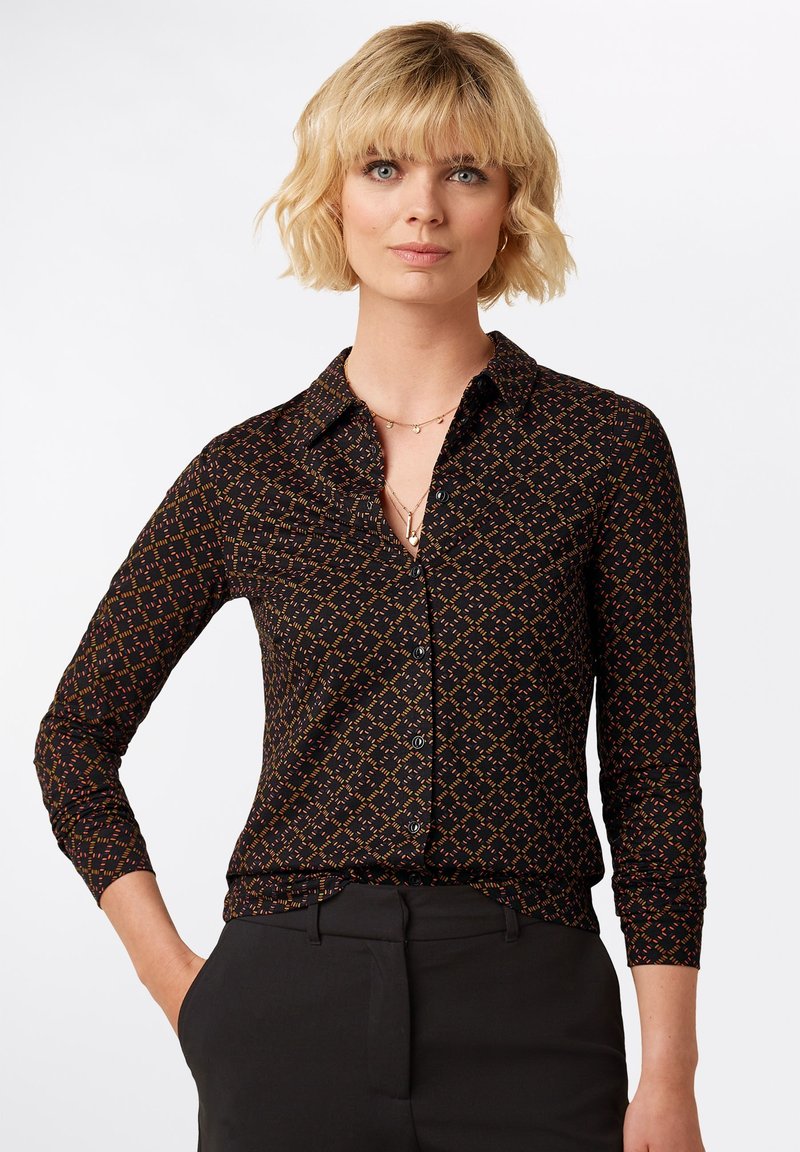 Camicia nera con bottoni, dotata di un motivo geometrico arancione e blu, con colletto, maniche lunghe e design aderente.