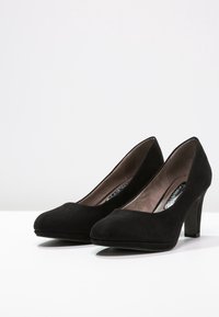 Svarta mocka högklackade pumps med rund tå och slät yta. Klackarna är av medelhöjd och har en klassisk silhuett.